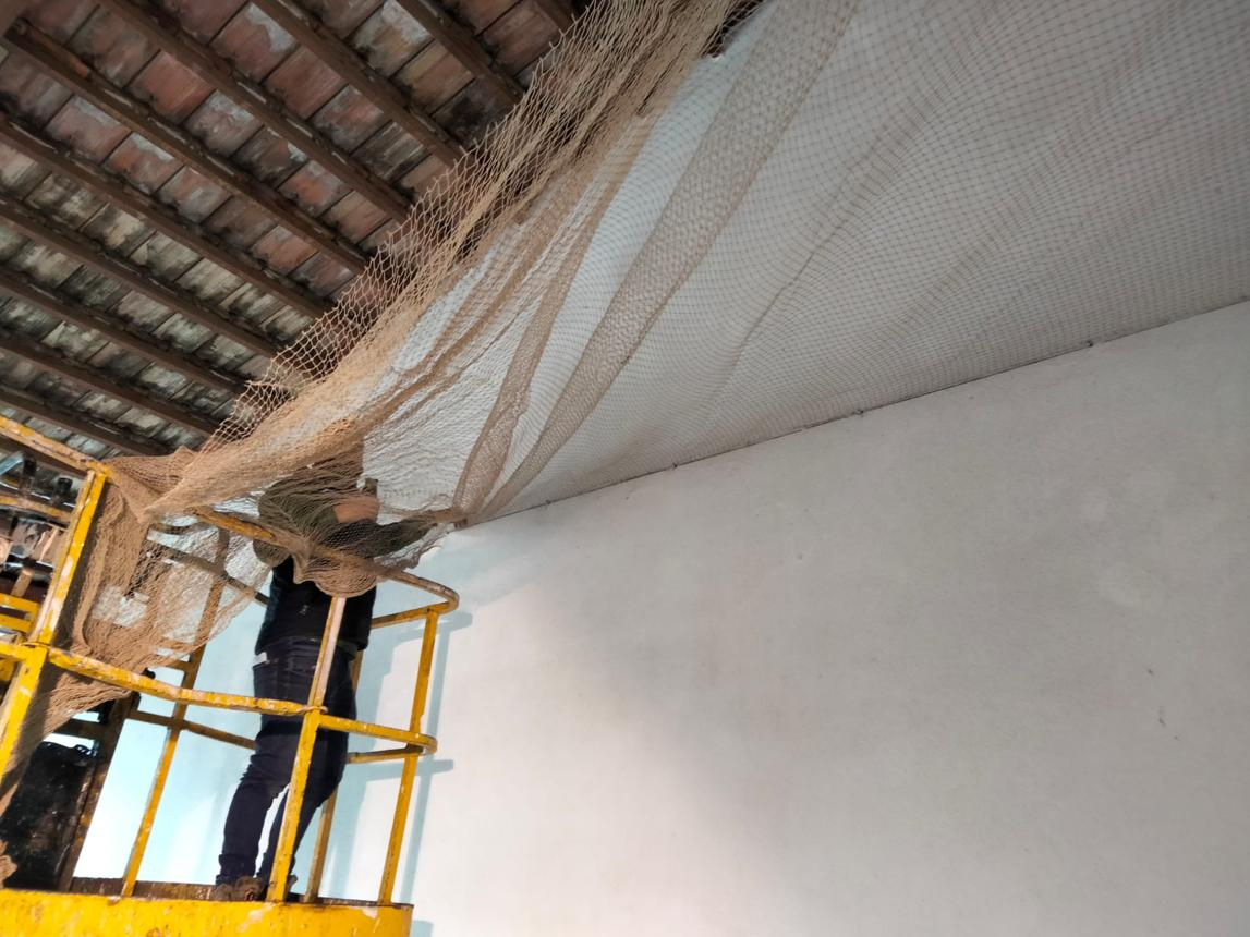 Bird netting installation across warehouse ceiling